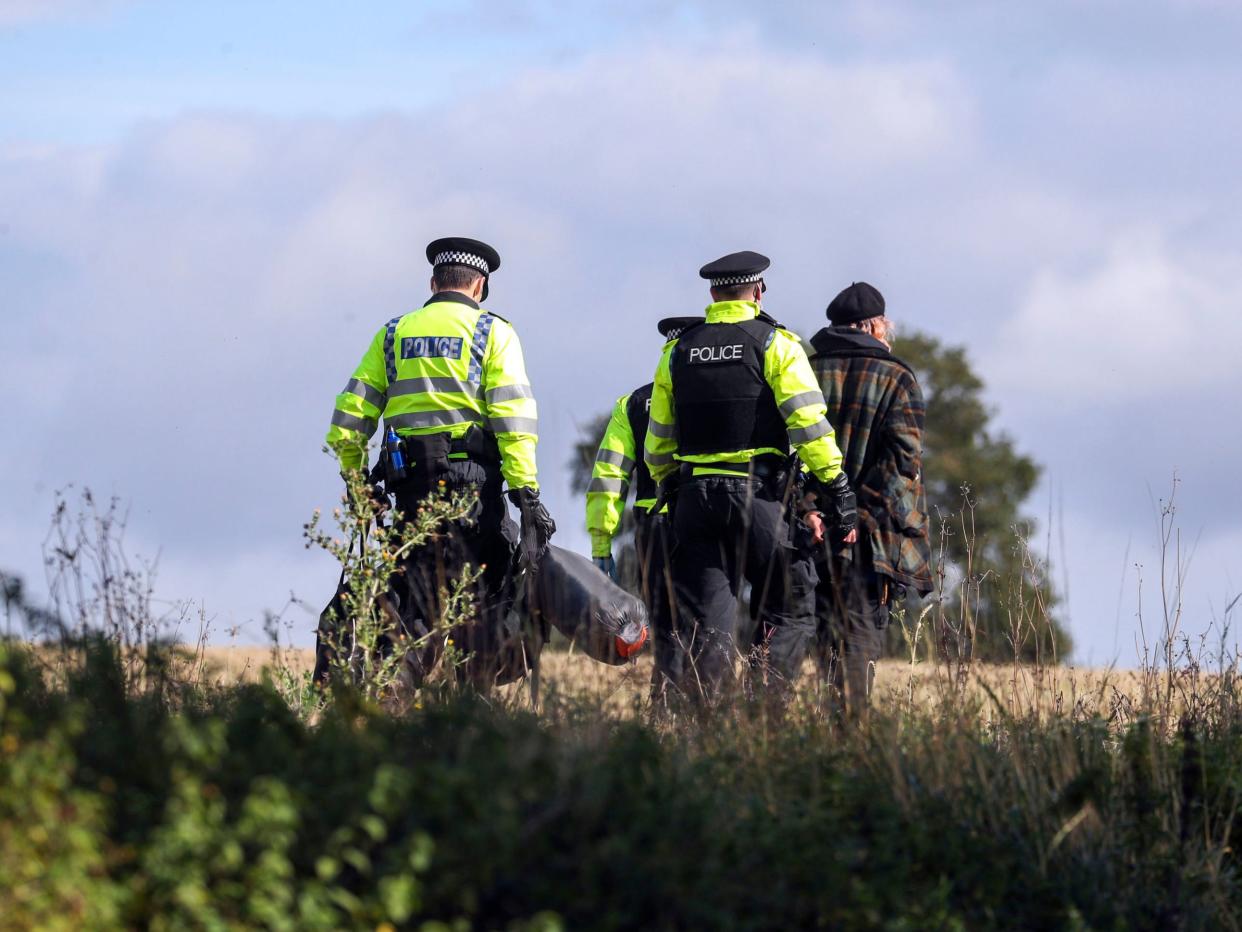 A protester is escorted off a HS2 construction site by police at Jones' Hill Wood in Buckinghamshire (PA)