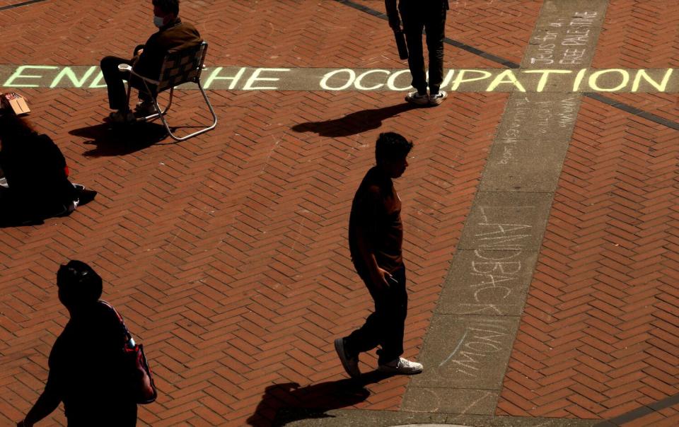 BERKELEY, CA - APRIL 26, 2024 - Students walk past a statement in chalk in front of Sproul