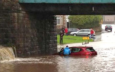 a car stuck in flood water under a railway bridge in Seaton, Cumbria - Credit: Martin A/PA