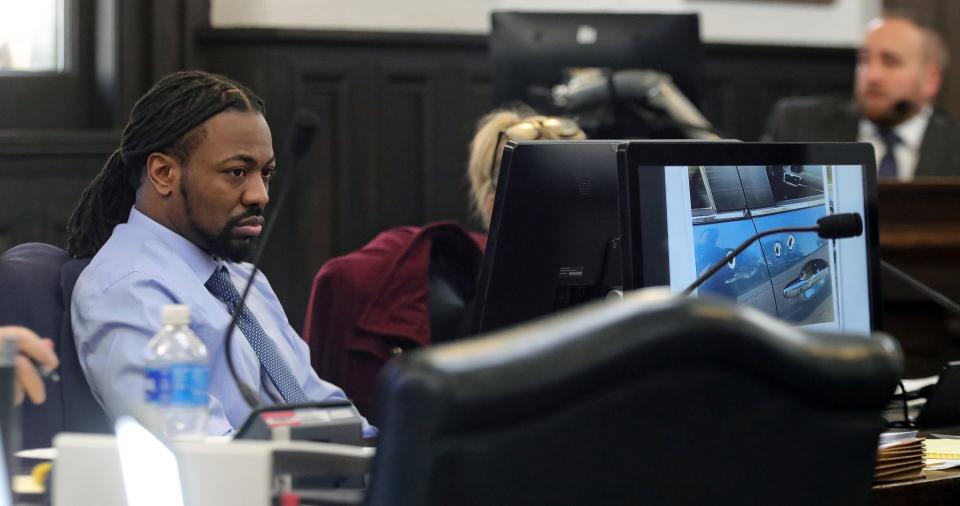 Dacarrei Kinard of Columbus, left, looks on as Norton Police Detective Ryan Connell goes over photographs showing bullet holes in the side of victim George Jenson’s vehicle during Kinard’s road rage murder trial Monday in Judge Kathryn Michael’s courtroom at the Summit County Courthouse.