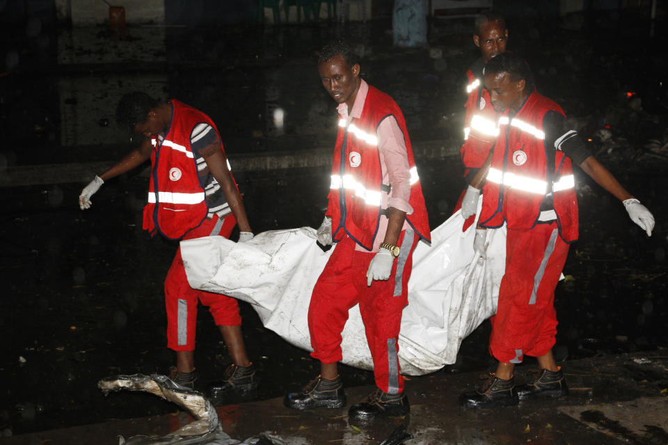 Medical workers carry a body after a car bomb, in Mogadishu, Somalia, Sunday Aug. 5, 2018. Two car bombs hit Somalia on Sunday, killing at least six people. Somalia's Islamic extremist rebels claimed responsibility for the first suicide car bomb blast that that killed four people when it exploded near the gate of a military base in Afgoye town, 30 kilometers (18 miles) northwest of Mogadishu. (AP Photo/Farah Abdi Warsameh)