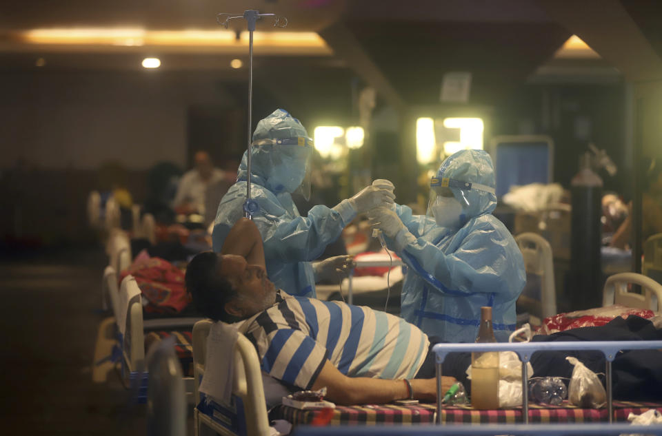 FILE - In this April 30, 2021, file photo, health workers attend to COVID-19 patients at a makeshift hospital in New Delhi, India. COVID-19 infections and deaths are mounting with alarming speed in India with no end in sight to the crisis. People are dying because of shortages of bottled oxygen and hospital beds or because they couldn’t get a COVID-19 test. (AP Photo/File)