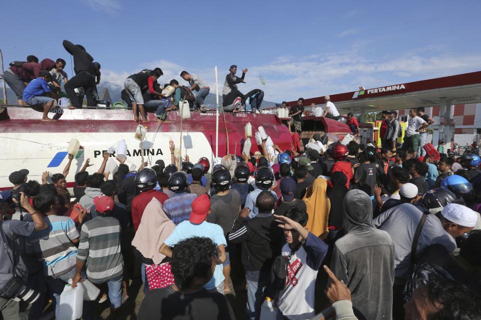 People take gasoline from a truck following a massive earthquake and tsunami in Palu, Central Sulawesi, Indonesia, Sunday, Sept. 30, 2018. Rescuers in Indonesia were scrambling Sunday to reach trapped victims screaming for help from collapsed buildings, while looters risked entering an unstable shopping mall to grab whatever they could find after a massive earthquake spawned a tsunami. (AP Photo/Tatan Syuflana)