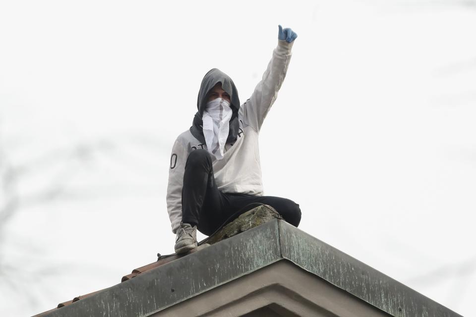 A man stands on the roof of the San Vittore prison during a protest in Milan, Italy, Monday, March 9, 2020. Italian penitentiary police say six inmates protesting virus containment measures at a northern Italian prison have died after they broke into the infirmary and overdosed on methadone. The protest Sunday in Modena was among the first of more than two-dozen riots at Italy’s overcrowded lock-ups that grew Monday. Human rights advocates have been warning that increasing tensions over fears of coronavirus were hitting inmates particularly hard, especially after restrictions were imposed on family visits to prevent transmissions. (AP Photo/Antonio Calanni)