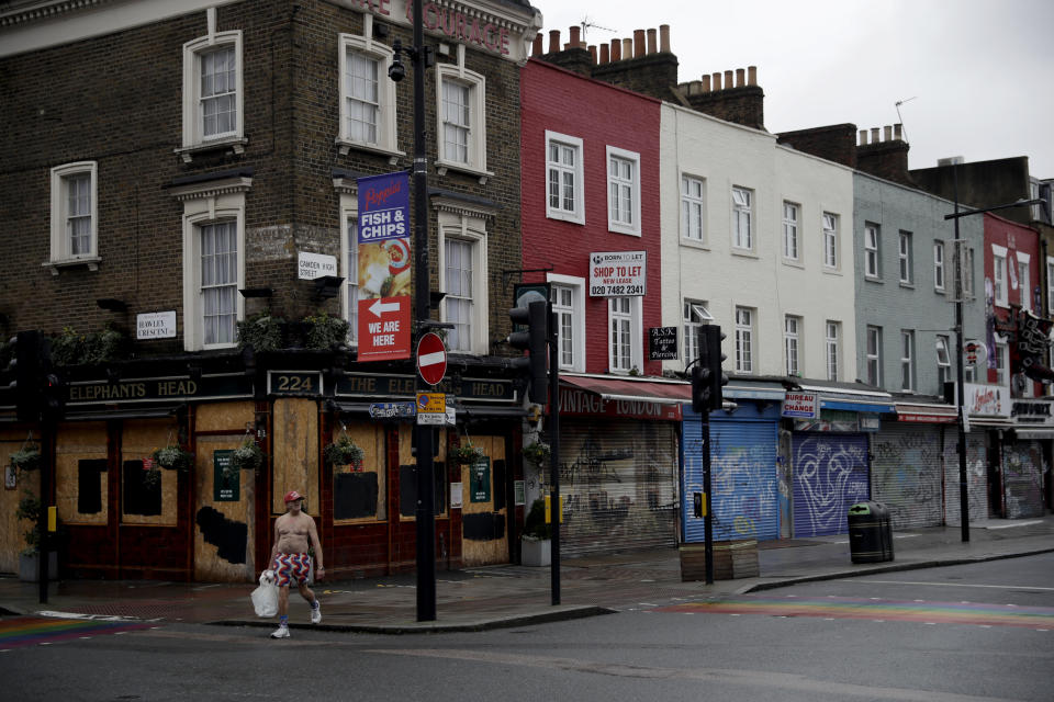 A man walks past temporarily closed shops and a pub in Camden Town, an area of London usually bustling with tourists and visitors to its market, Tuesday, Jan. 12, 2021, during England's third national lockdown since the coronavirus outbreak began. Britain, with over 81,000 dead, has the deadliest virus toll in Europe and the number of hospital beds filled by COVID-19 patients has risen steadily for more than a month. (AP Photo/Matt Dunham)