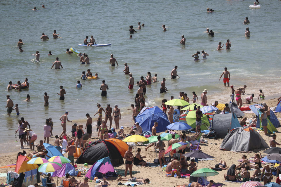 Crowds gather at the water's edge as hot weather draws crowds to the beach in Bournemouth, England, Thursday June 25, 2020. Coronavirus lockdown restrictions are being relaxed but people should still respect the distancing requirements between family groups. According to weather forecasters this could be the UK's hottest day of the year, so far, with scorching temperatures forecast to rise even further. (Andrew Matthews/PA via AP)
