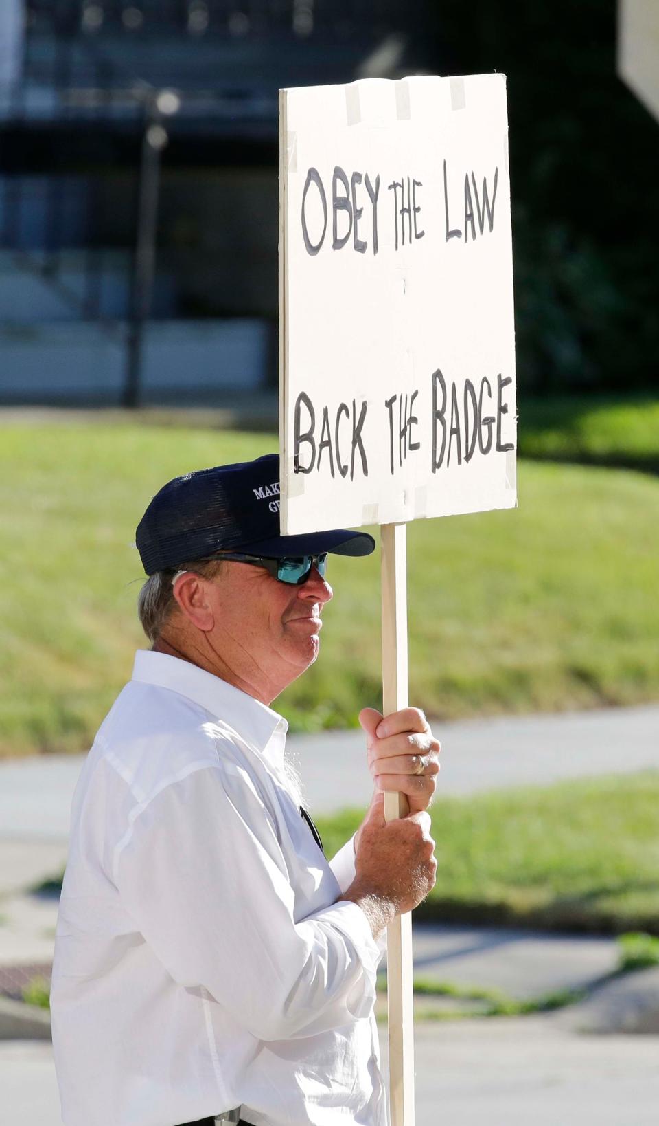 A pro-ICE man who also also backed the badge held a sign with his views, Friday, July 10, 2020, in Sheboygan, Wis. The group was against the agreement that the Sheboygan County Sheriff made with ICE on detaining immigrants.