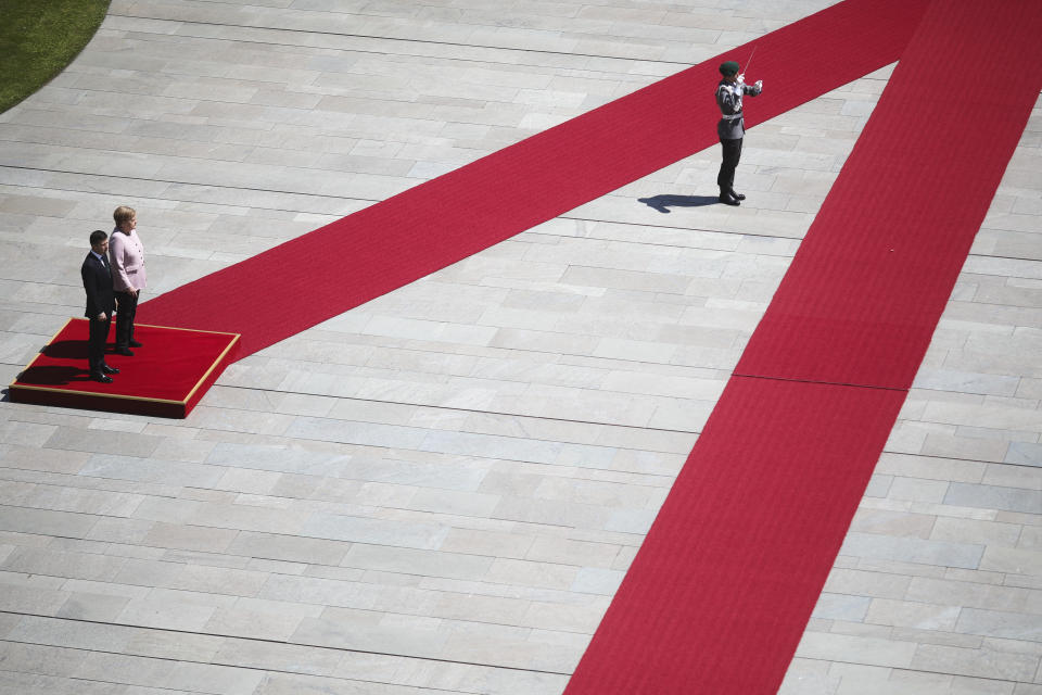 German Chancellor Angela Merkel, on the podium right, and Ukrainian President Volodymyr Zelenskiy, on the podium left, listen to the national anthems during the welcoming ceremony, prior to a meeting at the chancellery in Berlin, Germany, Tuesday, June 18, 2019. (AP Photo/Markus Schreiber)