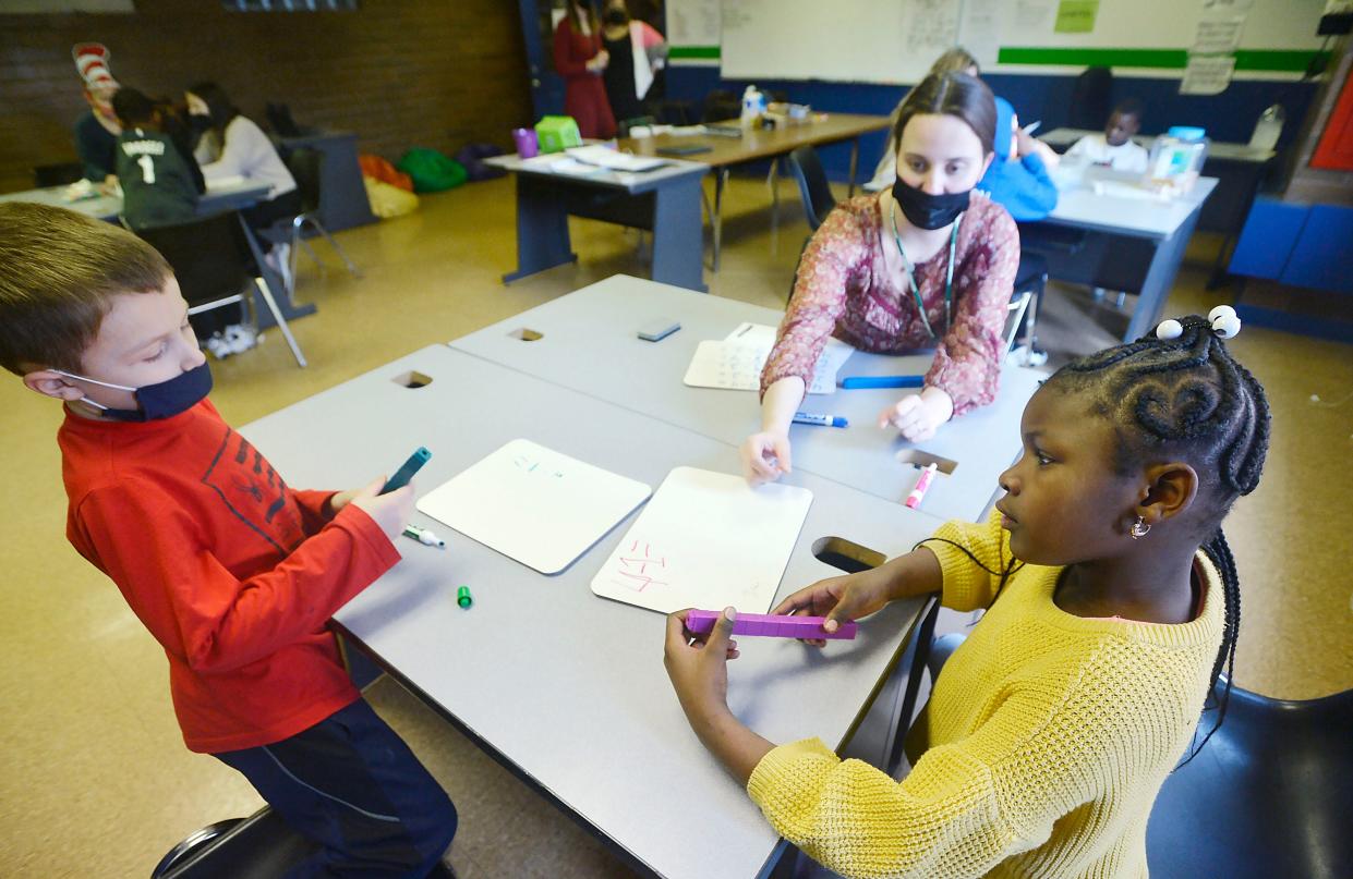 Nick Wisniewski, left, and Londyn Williams, right, then each 6 years old, work on math problems with Sydnee Hitchcock at the Booker T. Washington Center on March 2, 2022, in Erie. The Erie School District used pandemic-related federal funds to pay for the after-school programs at the Booker T. Washington Center and other community centers in Erie, but that funding is expiring, creating questions about whether the programs will continue.