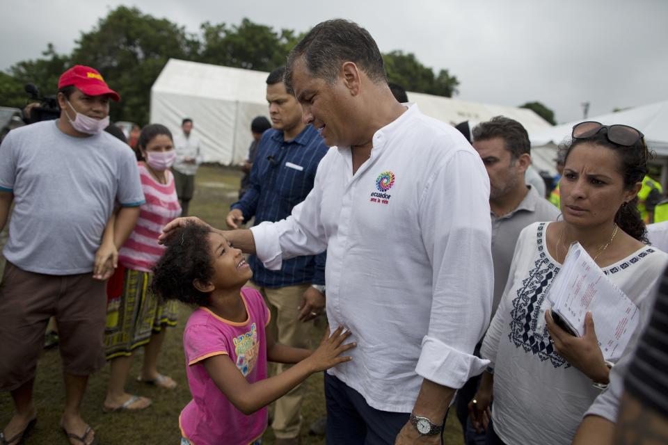 FILE - In this April 22, 2016 file photo, Ecuador's President Rafael Correa listens to a girl during a visit to a makeshift camp for people left homeless by the 7.8-magnitude earthquake, in Pedernales, Ecuador. Last year's devastating earthquake exacerbated Ecuador's fiscal woes, leading to layoffs and delays in payments at state-run contractors that has rippled throughout the economy. (AP Photo/Rodrigo Abd, File)