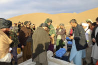 Afghan villagers receive food and shelters after their home was damaged by Monday's earthquake in the remote western province of Badghis, Afghanistan, Tuesday, Jan. 18, 2022. The United Nations on Tuesday raised the death toll from Monday's twin earthquakes in western Afghanistan, saying three villages of around 800 houses were flattened by the temblors. (Abdul Raziq Saddiqi)