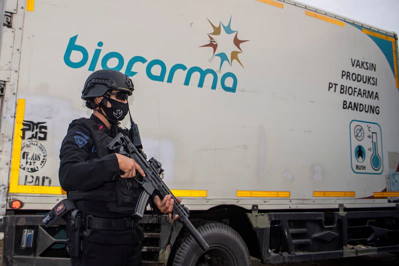 An armed police officer stands guard next to a truck containing Sinovac's vaccine for coronavirus disease (COVID-19) as it arrives at the cold room of Indonesia's local health department in Palembang