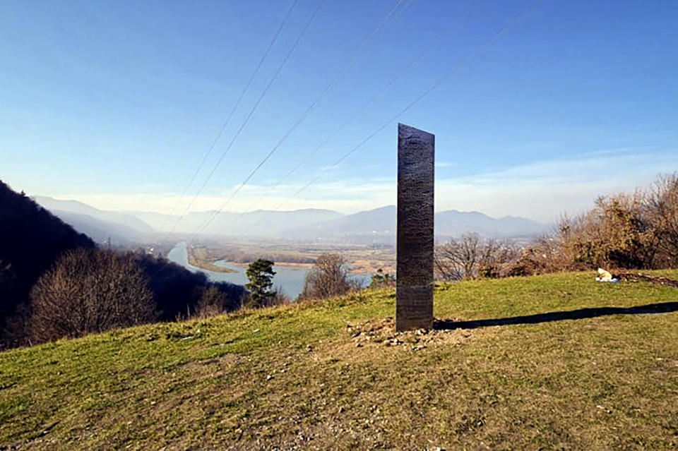 FILE - In this Nov. 27, 2020, file photo, a metal structure sticks out from the ground on the Batca Doamnei hill, outside Piatra Neamt, northern Romania. Days after the arrival and swift disappearance of two shining metal monoliths spotted half a world away from each other, another towering structure has popped up, this time at the pinnacle of a trail in Southern California. Its straight sides and height appear similar to one discovered in the Utah desert and another that was found in Romania. (Robert Iosub/ziarpiatraneamt.ro via AP, File)