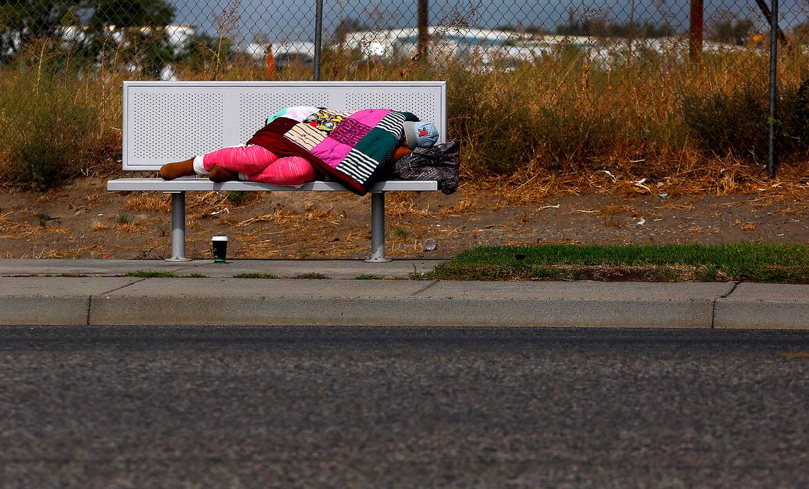 A woman sleeps on a transit stop bench on East Lewis Street in Pasco in September 2022.