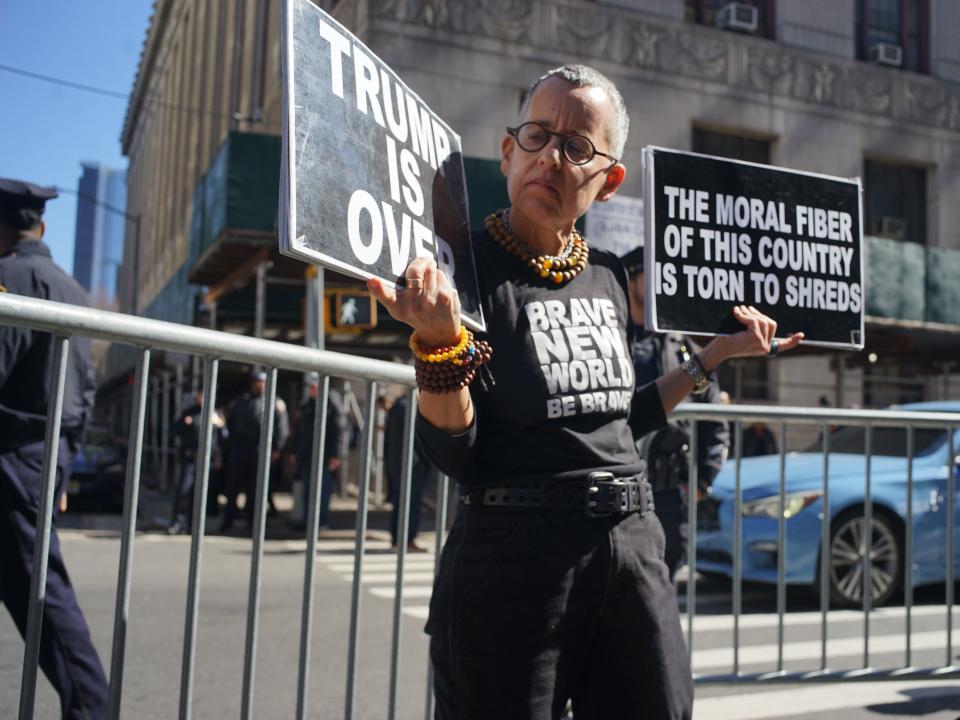 A person holds up a sign outside of Manhattan Criminal Court on March 21, 2023 following the news that Pres. Trump may face indictment.