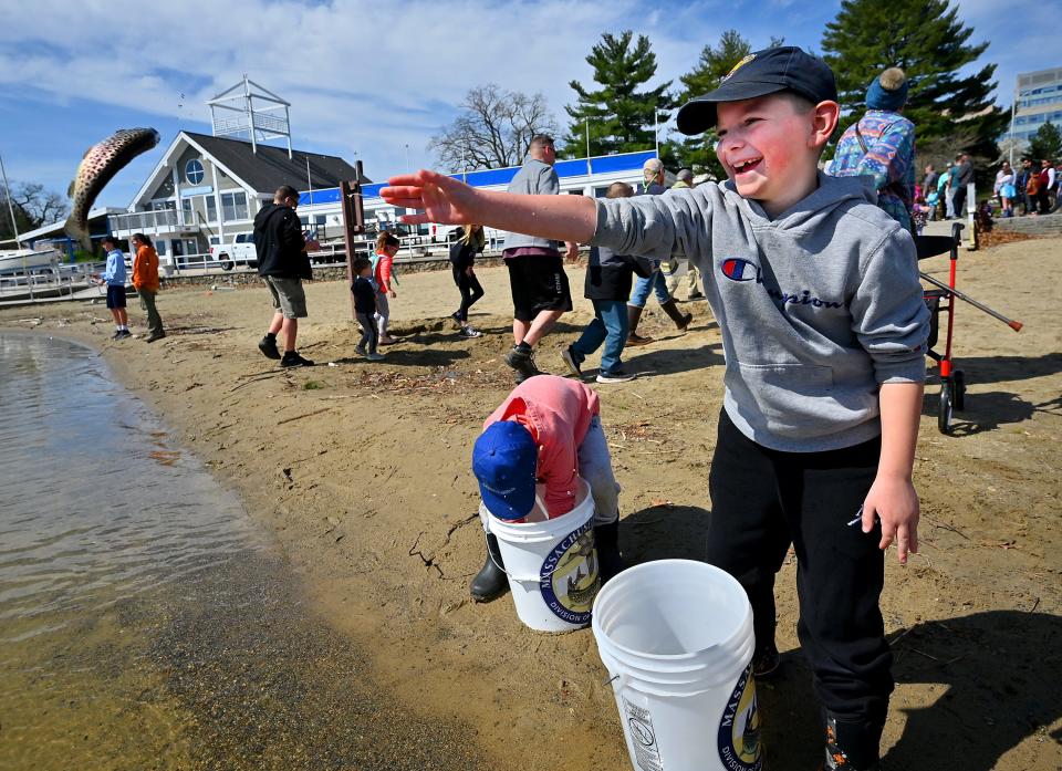 WORCESTER - Cormac O'Brien, 8, of West Boylston tosses in a trout as his brother, Henry, 5, tries to get one out of his bucket. They were among a couple hundred (at least) locals who showed up at Regatta Park to help restock Lake Quinsigamond with trout.