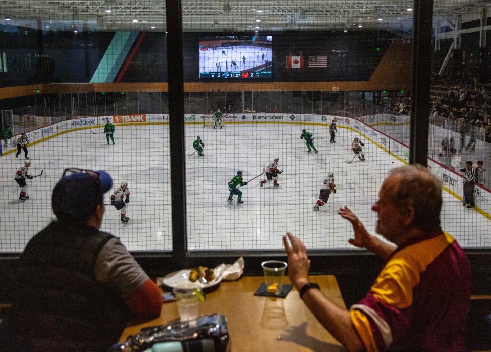 Hockey fans watch the Coachella Valley Firebirds play the Abbotsford Canucks from 32 Bar and Grill during the third period of their game at Kraken Community Iceplex in Seattle, Wash., Friday, Oct. 21, 2022. 