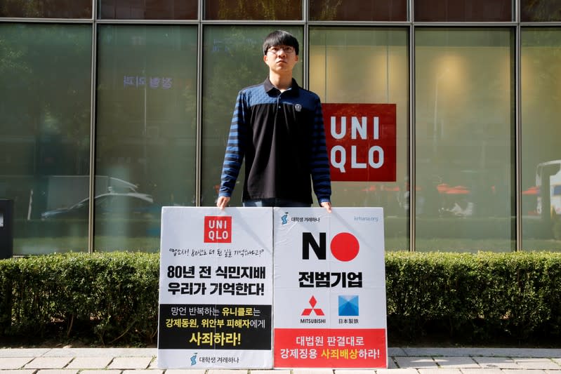 A university student Bang Seulkichan stands with banners as a protest against recent released Uniqlo commercial in front of a Uniqlo store in Seoul