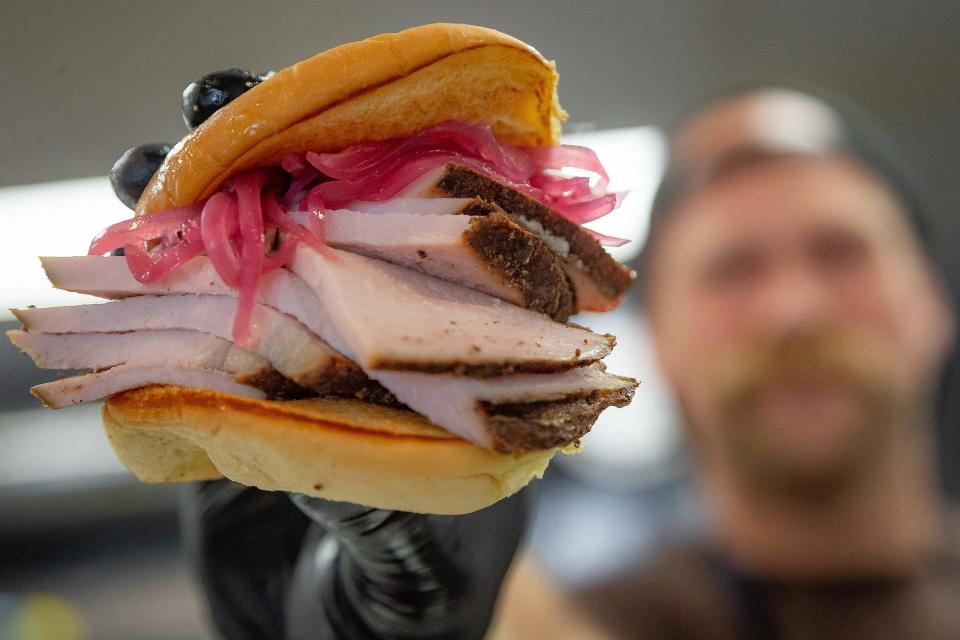 Chef Rick Mace displays a jerk turkey breast sandwich at his new Tropical BBQ market in downtown West Palm Beach.