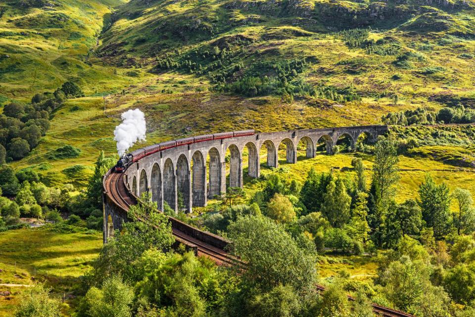 glenfinnan railway viaduct in scotland with a steam train