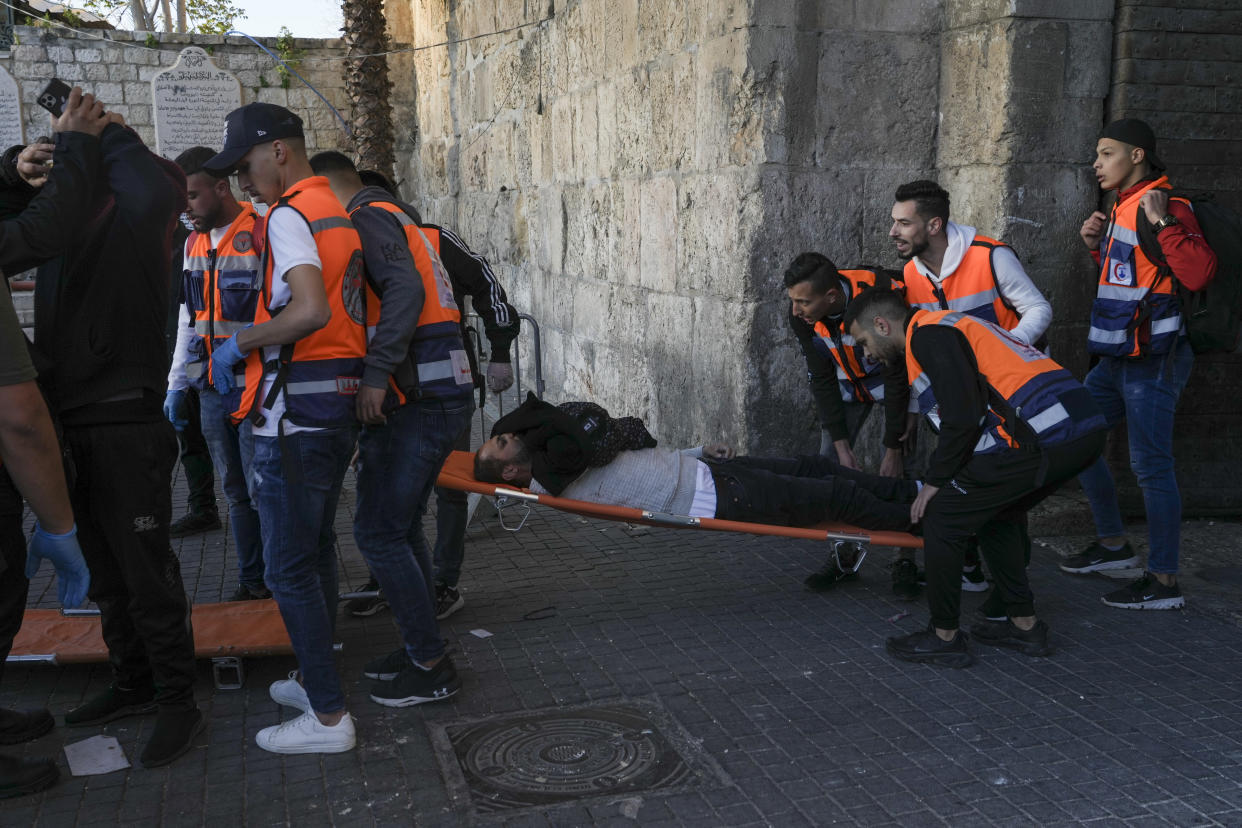 Palestinians evacuate a wounded man during clashes with Israeli security forces, outside Al Aqsa Mosque compound in Jerusalem's Old City Friday, April 15, 2022. (AP Photo/Mahmoud Illean)