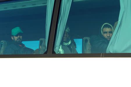 Migrants, who were stranded on the Greek-Macedonian border, are seen through a bus window after a police operation near the village of Idomeni, Greece, December 9, 2015. REUTERS/Alexandros Avramidis