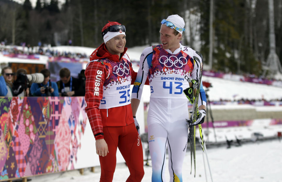 Gold medalist Switzerland's Dario Cologna, left, and silver medalist Sweden's Johan Olsson walk in the finish area after completing the men's 15K classical-style cross-country race at the 2014 Winter Olympics, Friday, Feb. 14, 2014, in Krasnaya Polyana, Russia. (AP Photo/Gregorio Borgia)