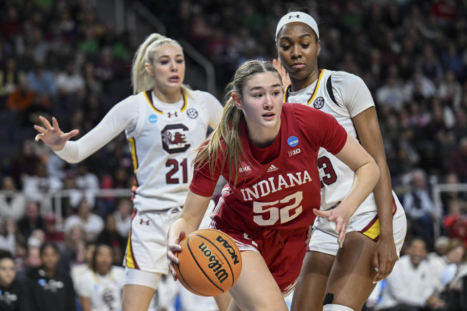 Indiana forward Lilly Meister (52) drives the ball against South Carolina forward Chloe Kitts (21) and guard Bree Hall (23) during the first quarter of a Sweet Sixteen round college basketball game during the NCAA Tournament, Friday, March 29, 2024, in Albany, N.Y. (AP Photo/Hans Pennink)