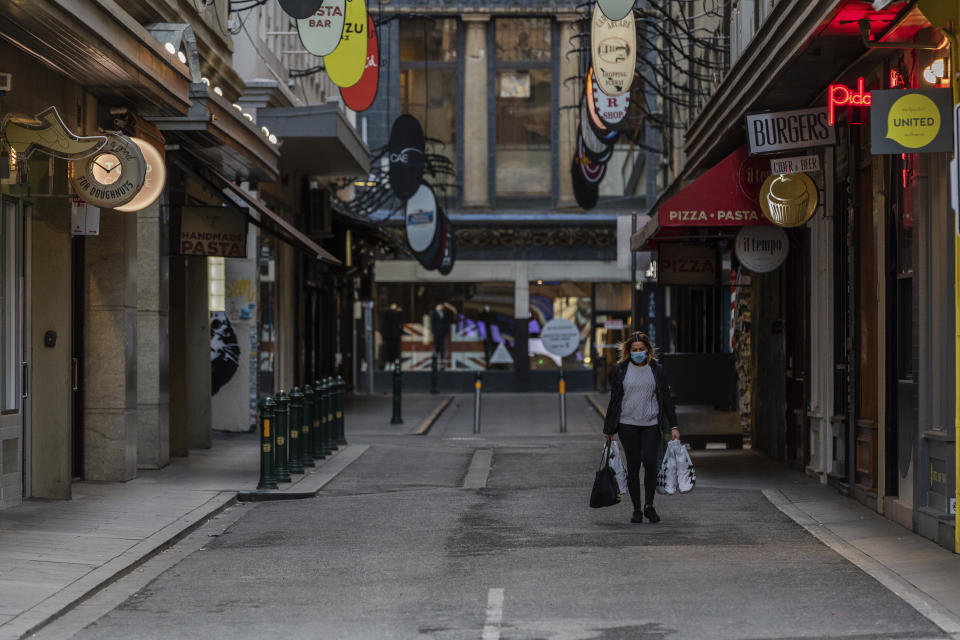 A lone shopper walks down the usually busy Degraves Street laneway fame for its cafe's and coffee during lockdown in Melbourne, Australia, Wednesday, Aug. 5, 2020. Victoria state, Australia's coronavirus hot spot, announced on Monday that businesses will be closed and scaled down in a bid to curb the spread of the virus. (AP Photo/Asanka Brendon Ratnayake)