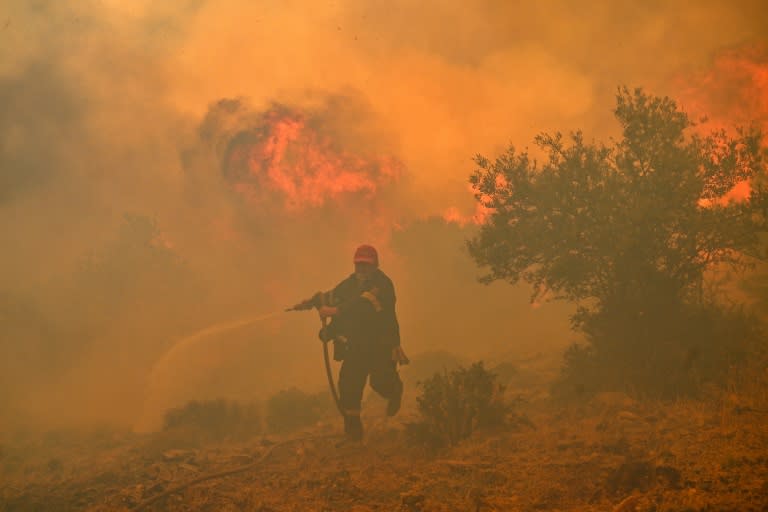 Un bombero huye de las llamas de un incendio en Néa Péramos, cerca de Atenas, el 19 de julio de 2023 (Louisa Gouliamaki)