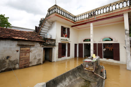 Poeple sit on a window of their flooded house after a heavy rainfall caused by Son Tinh storm in Ninh Binh province, Vietnam. REUTERS/Kham