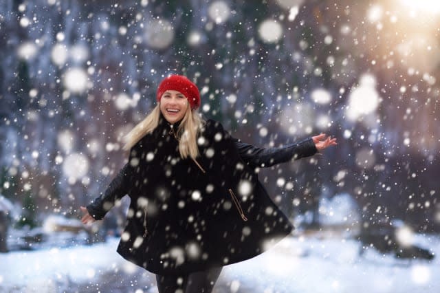 happy and energic woman in winter day enjoying the snowflakes and the december.wearing warm clothing, expressing positivity.phot