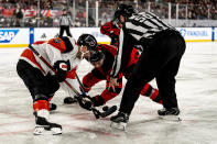 Philadelphia Flyers right wing Travis Konecny, left, and New Jersey Devils center Nico Hischier (13) face off in the first period of an NHL Stadium Series hockey game in East Rutherford, N.J., Saturday, Feb. 17, 2024. (AP Photo/Peter K. Afriyie)