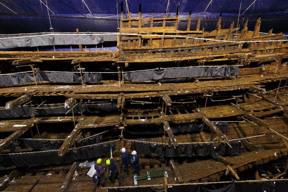 Conservators stand inside the hull of the Tudor warship, The Mary Rose. Part of the wreckage was raised from the seabed of the Solent in 1982. Visitors will be able to see the ship through glass windows (PA)