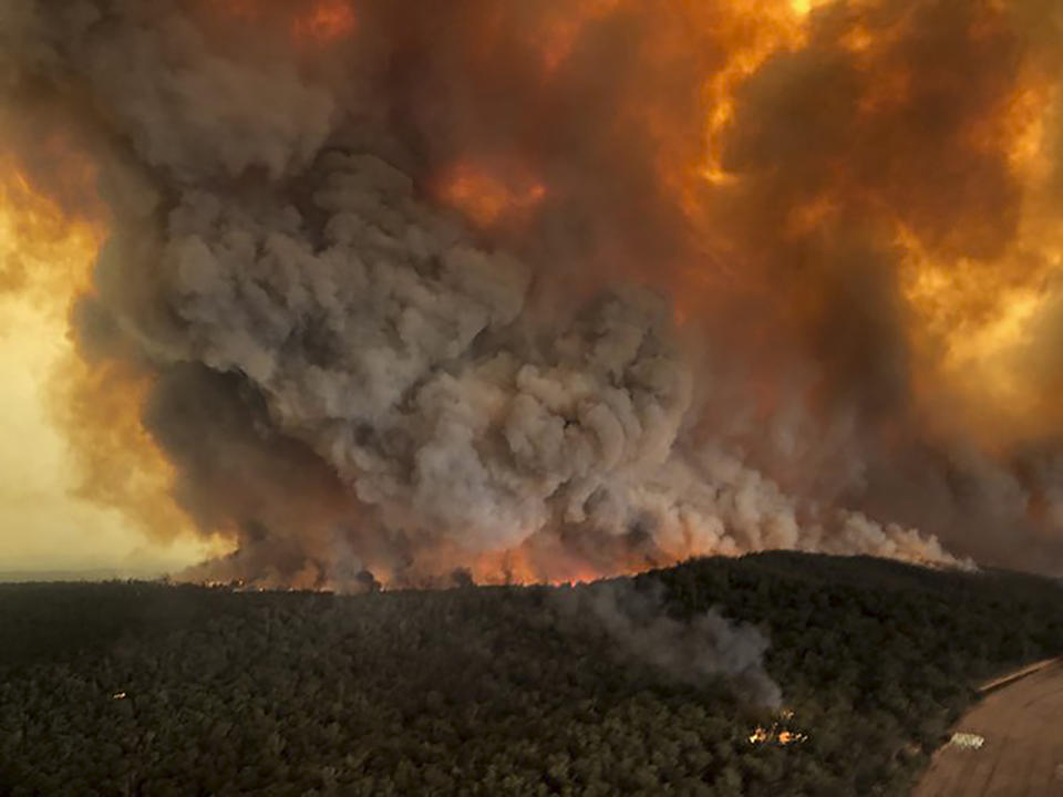 FILE - In this Monday, Dec. 30, 2019, aerial file photo, wildfires rage under plumes of smoke in Bairnsdale, Australia. U.S. officials said Tuesday, Jan. 7, 2020 they planning to send at least 100 more firefighters to Australia to join 159 already there battling blazes that have killed multiple people and destroyed thousands of homes. (Glen Morey via AP, File)