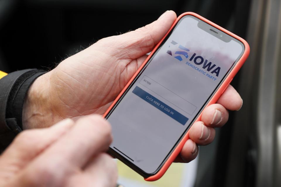 Precinct captain Carl Voss, of Des Moines, Iowa, holds his iPhone that shows the Iowa Democratic Party's caucus reporting app Tuesday.