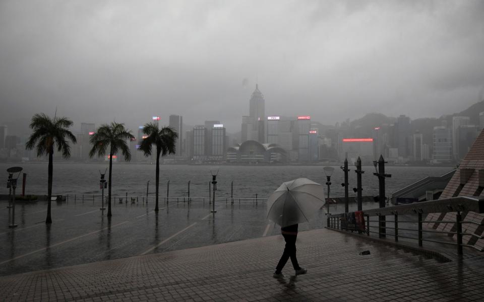 A person holding an umbrella walks in the rain at a waterfront, amid a typhoon warning on the 25th anniversary of the former British colony's handover to Chinese rule, in Hong Kong, China July 1, 2022. REUTERS/Paul Yeung - REUTERS/Paul Yeung