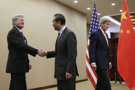 U.S. Secretary of State John Kerry (R) walks past as Chinese Foreign Minister Wang Yi (C) shakes hands with U.S. Ambassador to China Max Baucus before their bilateral meeting at the Ministry of Foreign Affairs in Beijing January 27, 2016. REUTERS/Andy Wong/Pool