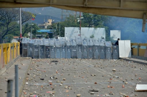 Venezuelan police sought protection behind their shields from a hail of rocks thrown by protesters at the Simon Bolivar international bridge across from Cucuta, Colombia