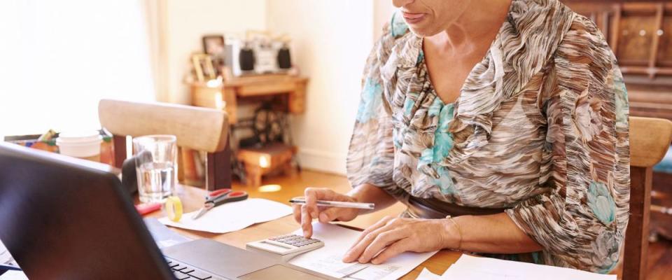 Woman crunches numbers for her emergency fund in her home office.