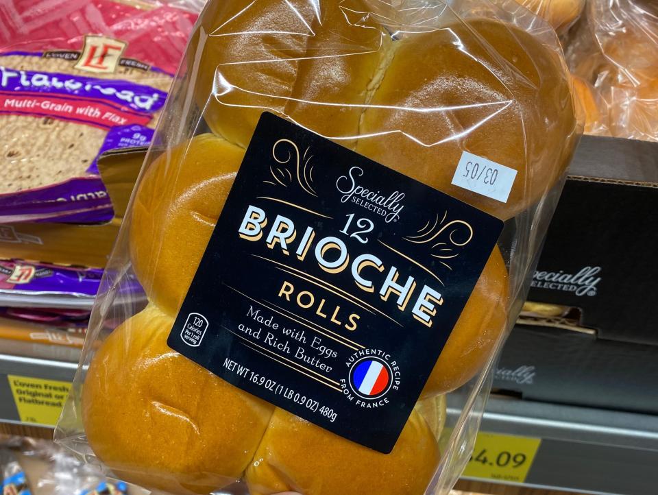 Hand holding pack of brioche buns at Aldi