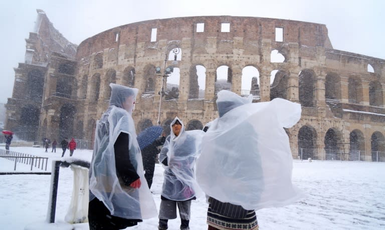 Tourists outside the Colosseum in Rome as snow falls on the Italian capital for the first time in six years