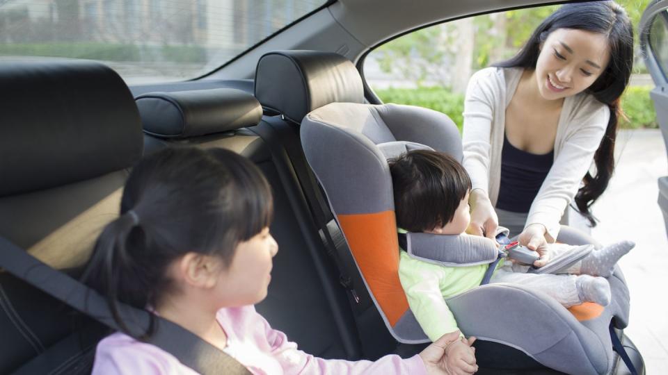 mother putting child in car seat