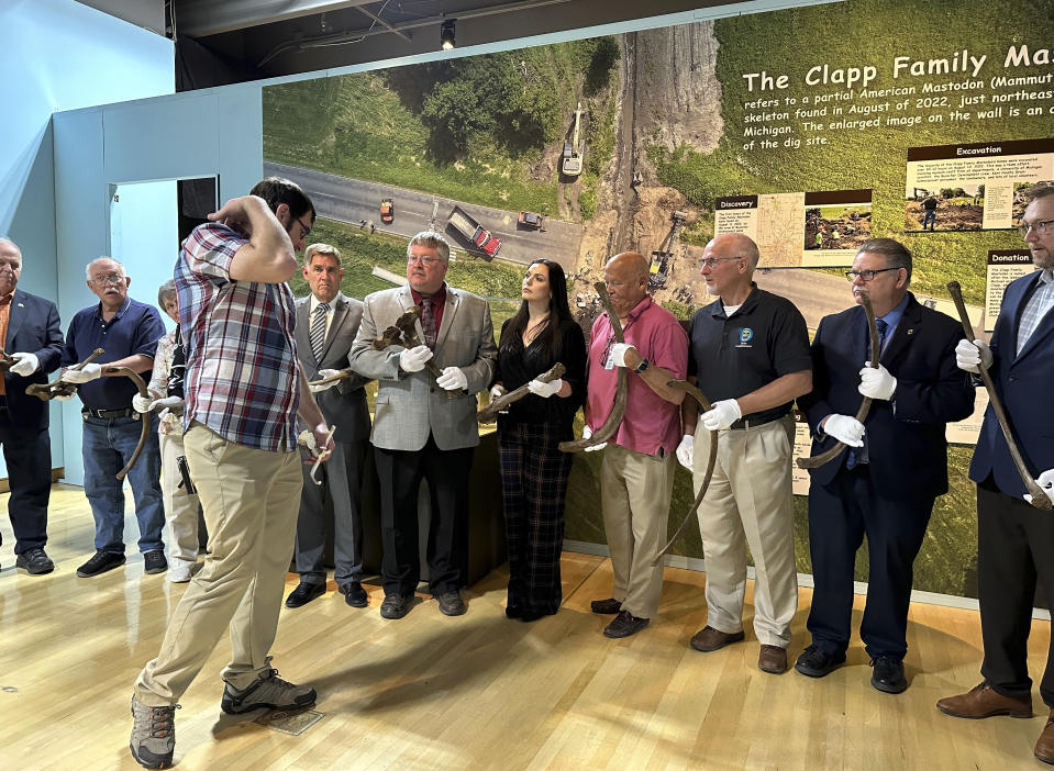 Cory Redman, foreground, science curator at the Grand Rapids Public Museum, discusses the anatomy of a mastodon while speaking with officials at the museum on Thursday, May 18, 2023, in Grand Rapids, Mich. Mastodon bones on display at GRPM were unearthed last year during a drainage dig in western Michigan and belonged to a juvenile mastodon that lived 13,000 years ago. (AP Photo/Mike Householder)