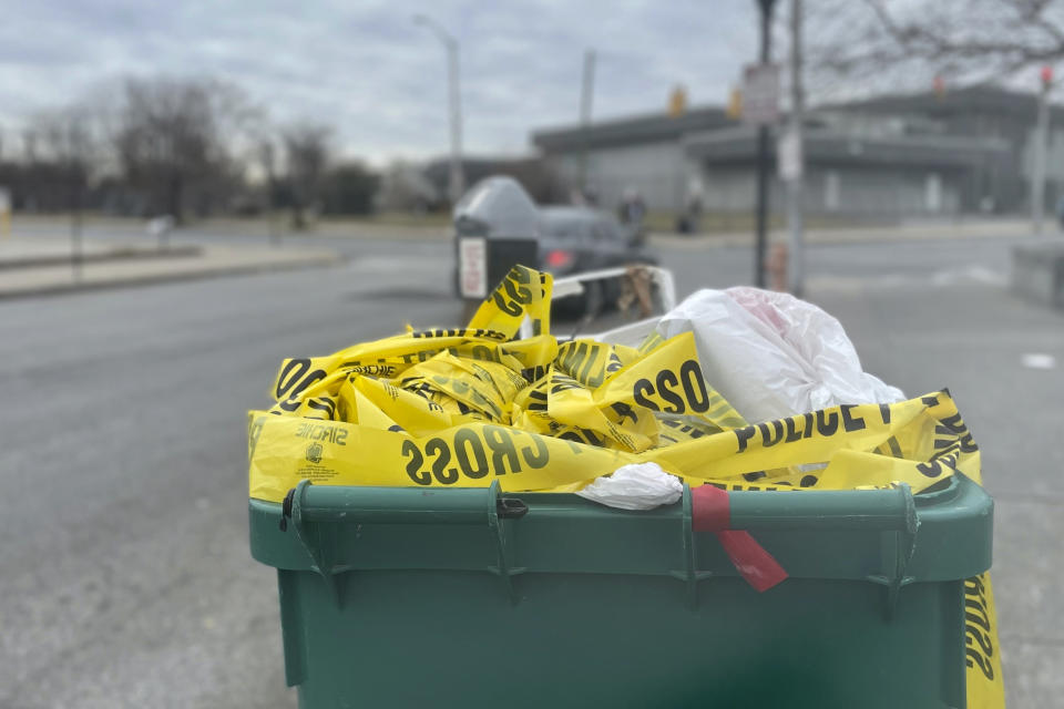 Crime tape spills out of a trash can Monday, Jan. 30, 2023, at the scene of a Saturday shooting in west Baltimore. A weekend shooting in west Baltimore’s Upton neighborhood killed two people and left three others injured, including two young children whose mother was hospitalized in critical condition and later died. (AP Photo/Lea Skene)
