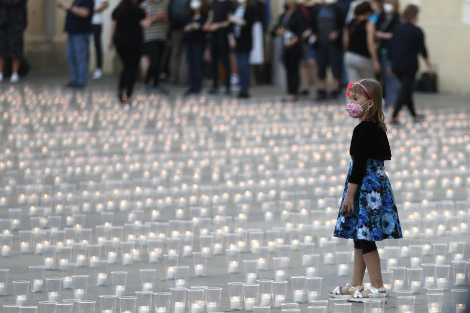 A young girl walks to light up candles to commemorate victims of the COVD-19 pandemic at the Prague Castle in Prague, Czech Republic, Monday, May 10, 2021. The Czech Republic is massively relaxing its coronavirus restrictions as the hard-hit nation pays respect to nearly 30,000 dead. (AP Photo/Petr David Josek)