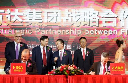 Wang Jianlin (C, behind), chairman of the Wanda Group, talks with Li Jinsheng, deputy director of Chinese Basketball Association, as FIBA Secretary General Patrick Baumann (L,front) and President of Wanda Sports Holding Philippe Blatter (R, front) sign documents during a signing ceremony in Beijing, China June 16, 2016. REUTERS/Jason Lee