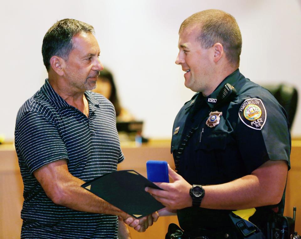 Anthony DiLorenzo shakes Portsmouth police officer Thompson "T.J." Potter's hand Tuesday, July 17, 2018 after praising first responders who rescued his son from underneath a 400-pound boulder at his home property. DiLorenzo, well known for years in Portsmouth and across New Hampshire, said he's the high bidder for the McIntyre federal building property on Daniel Street.