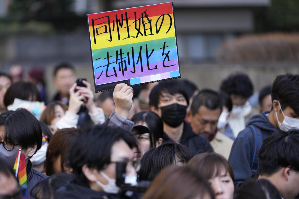 A supporter for the LGBTQ+ community holds up a poster as plaintiffs speak in front of media members by the main entrance of the Tokyo district court after hearing the ruling regarding LGBTQ+ marriage rights, in Tokyo, Thursday, March 14, 2024. The poster reads, "Legalize the same-sex marriage." The Japanese court on Thursday ruled that not allowing same-sex couples the same marital benefits as heterosexuals violates their fundamental right to have a family, but the current civil law did not take into consideration sexual diversity and is not clearly unconstitutional, a partial victory for Japan's LGBTQ+ community calling for equal marriage rights. (AP Photo/Hiro Komae)