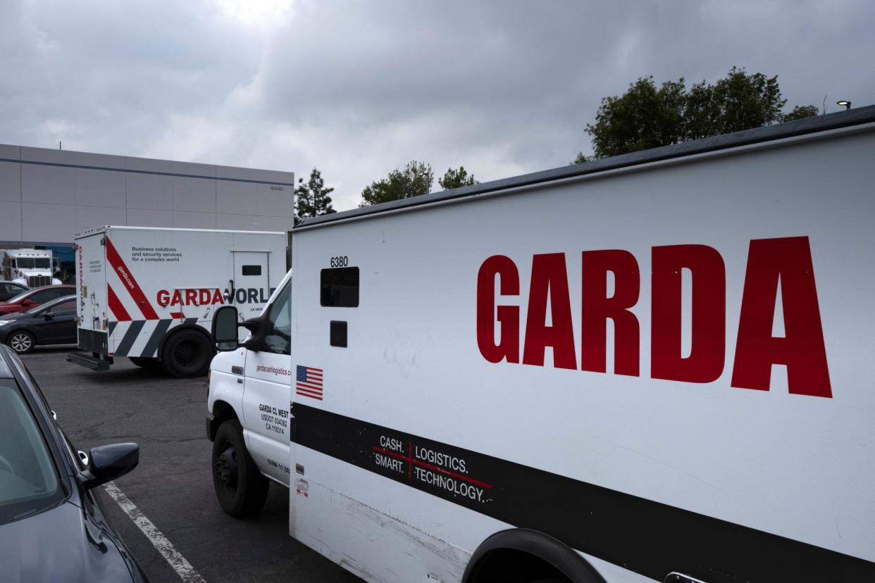 <span>Armored trucks are parked outside the offices of GardaWorld in the Sylmar section of Los Angeles.</span><span>Photograph: Richard Vogel/AP</span>